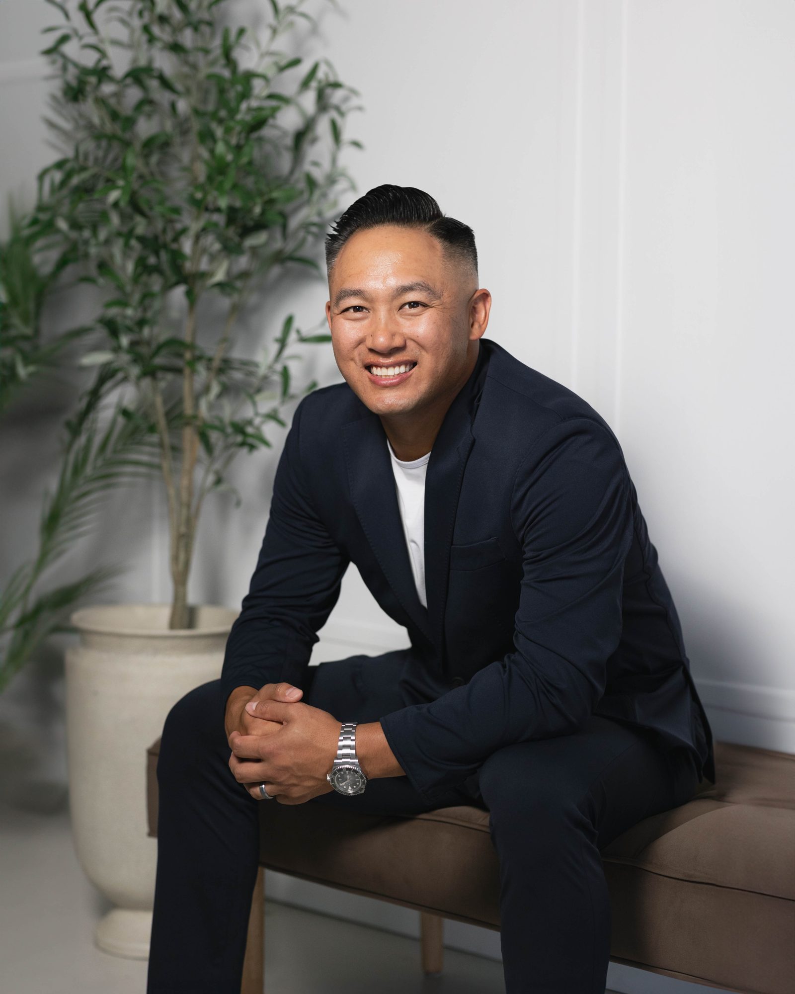 Steven Yee seated on a bench in a navy suit